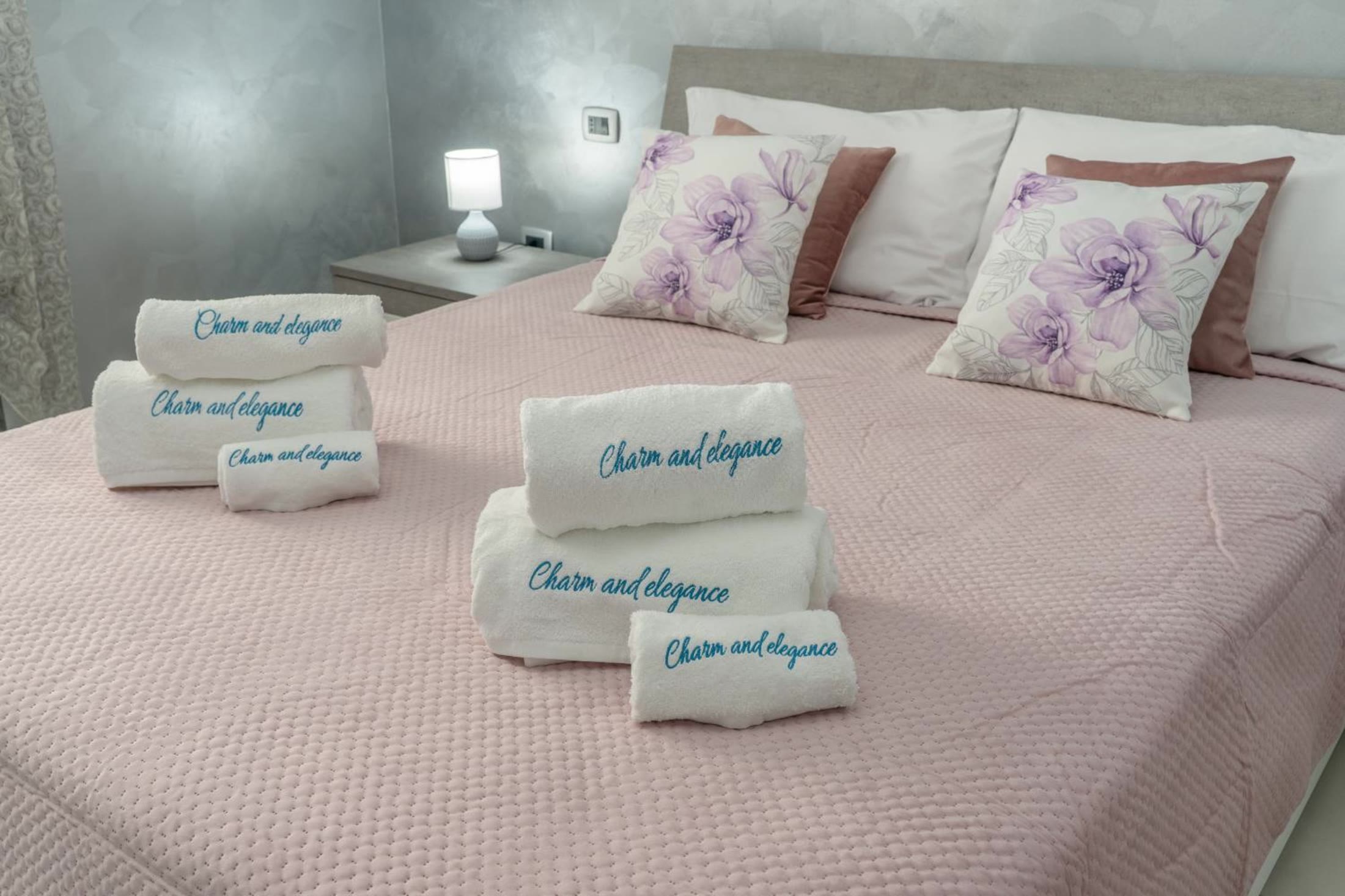 Gli asciugamani ricamati con il nome della villa, sul copriletto rosa della camera Nuvola