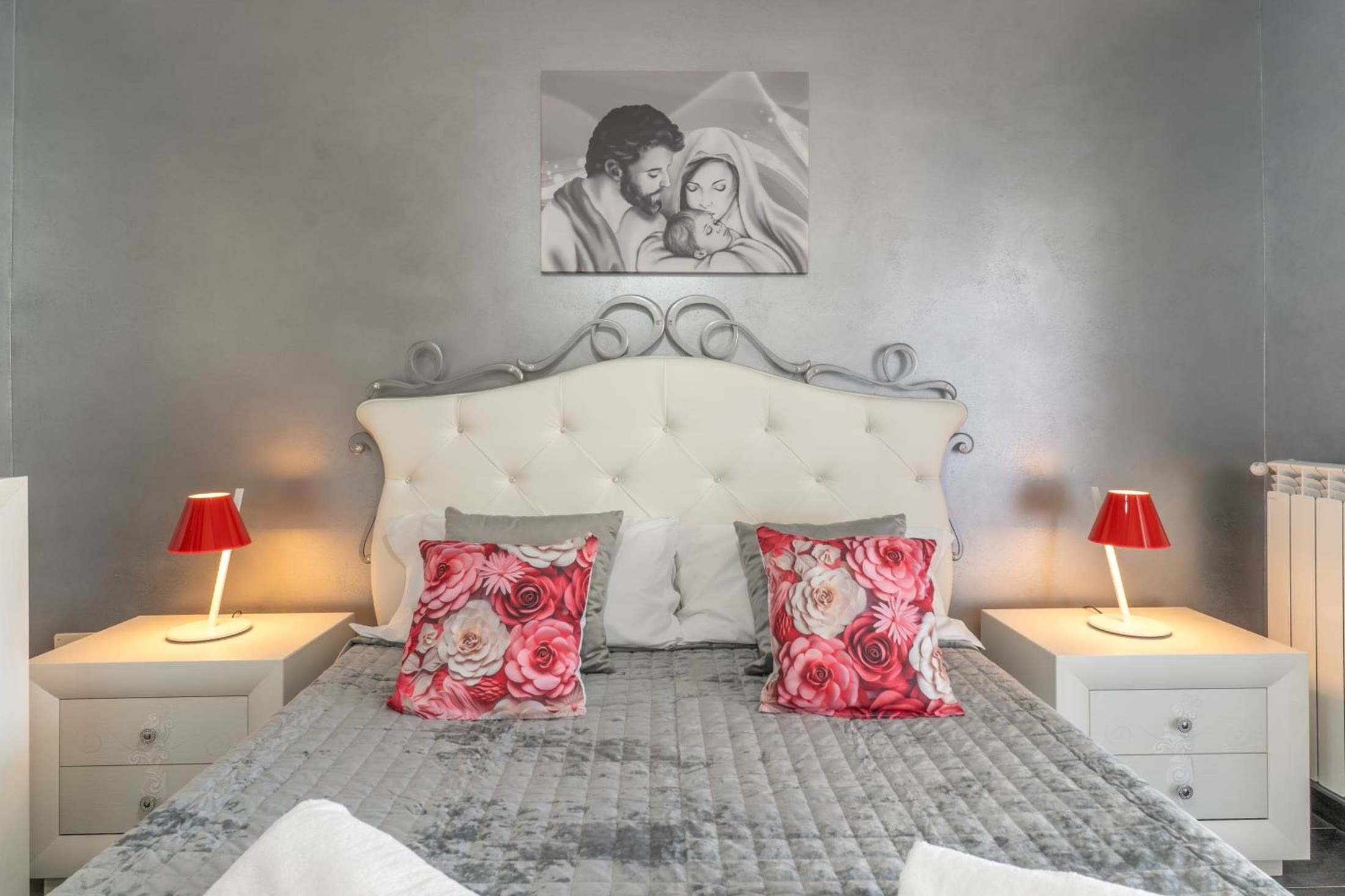 Camera Sole: letto matrimoniale con la testata capitonnè e le lampade rosse