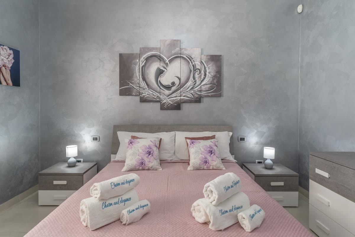 Camera Nuvola: letto matrimoniale con il copriletto rosa e il quadro a cuore