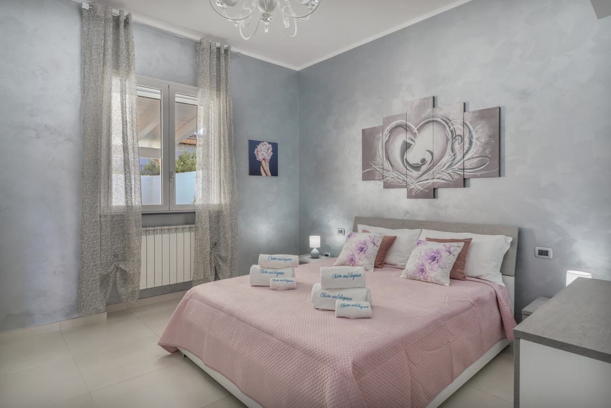Camera Nuvola: la finestra, il quadro a cuore e il letto con il copriletto rosa