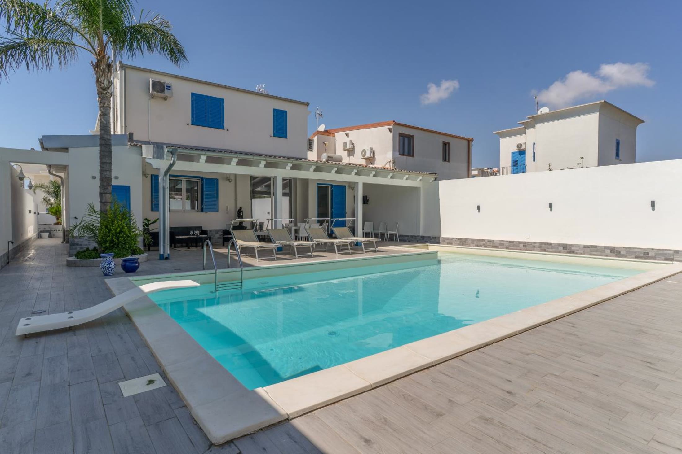 La piscina privata davanti alla villa, con la palma e il pergolato