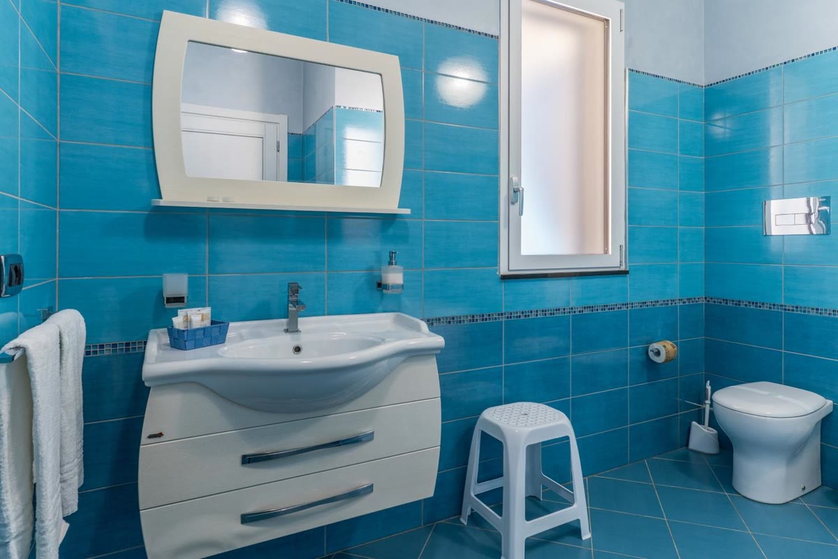 The blue bathroom: washbasin with mirror, toilet and window