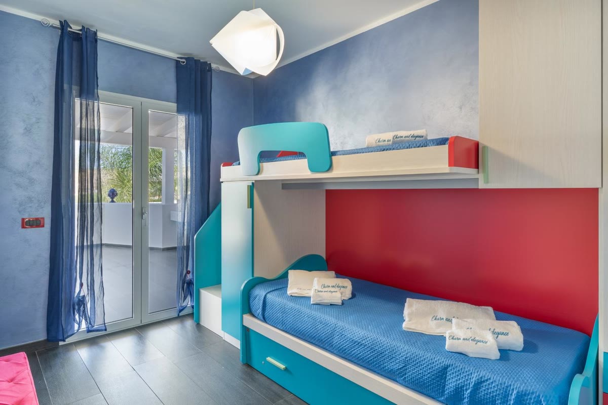 Arcobaleno bedroom: turquoise and red bunk beds and the French window