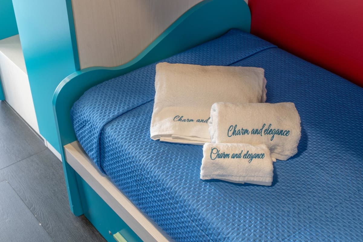 Towels embroidered with the villa's name, on a bed in the Arcobaleno room