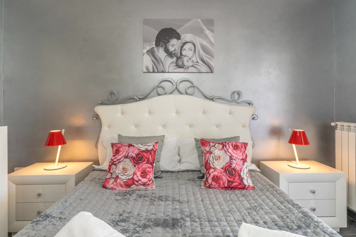 Sole bedroom: double bed with a buttoned headboard and red lamps