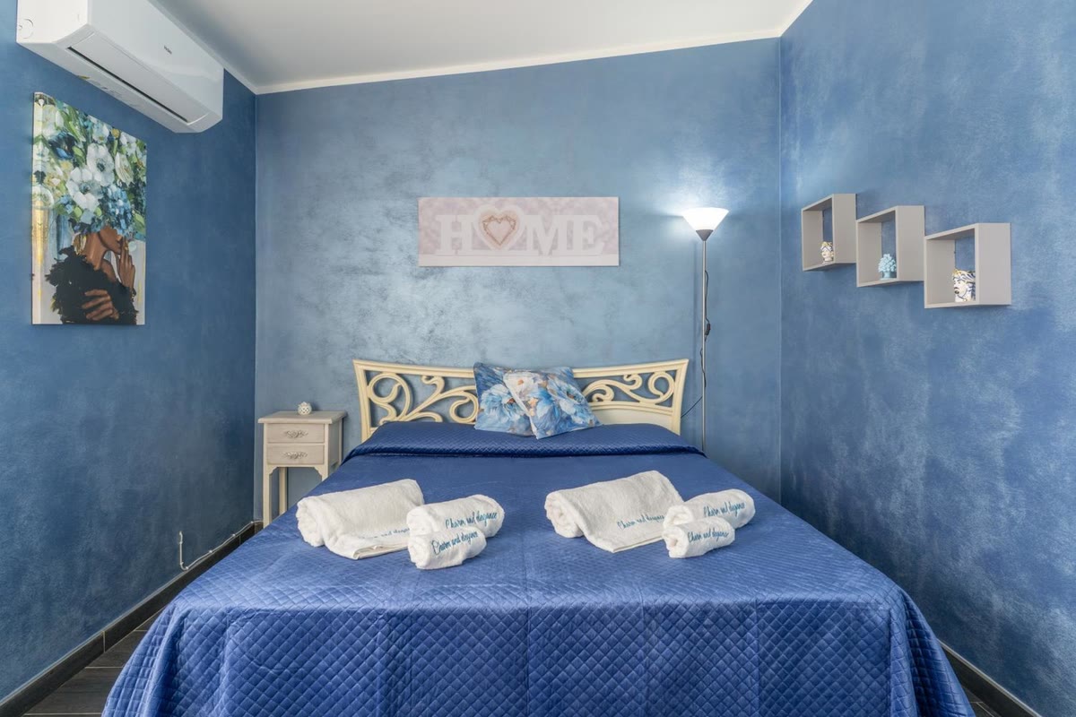 Stella bedroom: double bed with a wrought-iron headboard and blue walls
