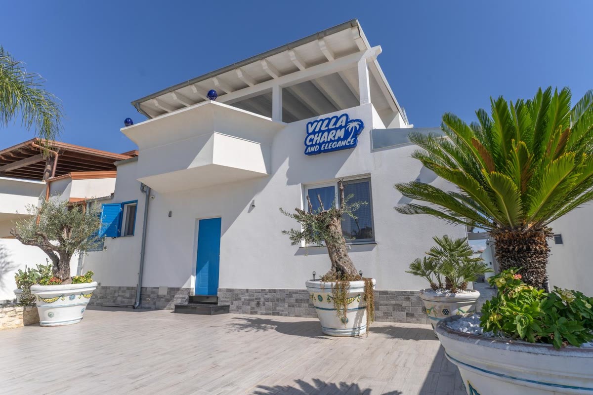 The front with the villa's sign, the potted olive tree and the blue door