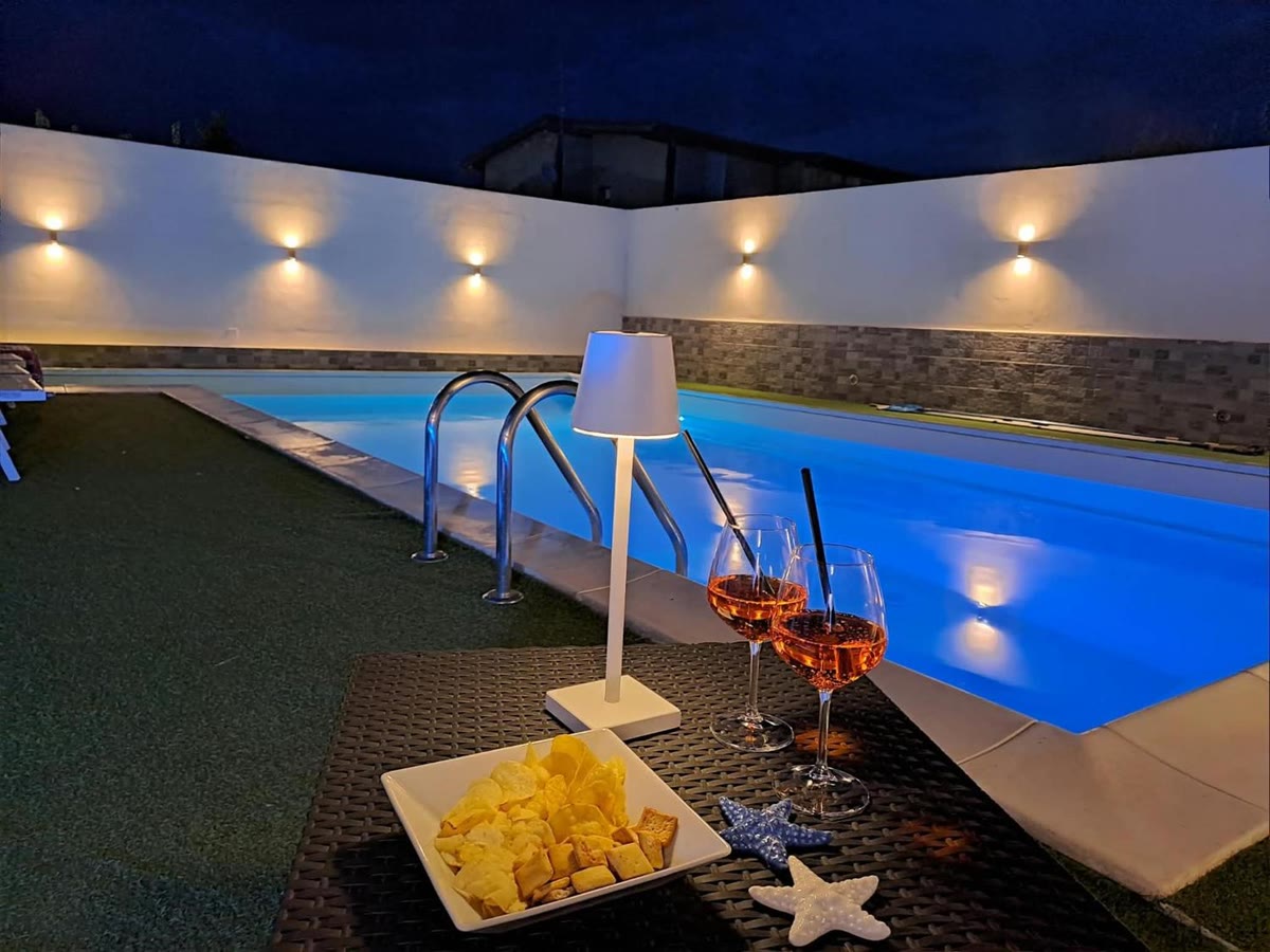 The pool in the evening, lit up, with drinks by the water